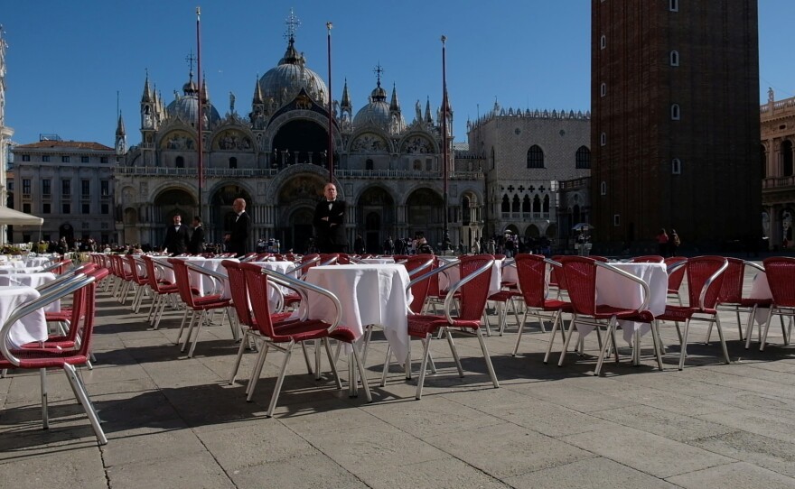 Waiters stand by an empty restaurant in Venice's St. Mark's Square, which would normally be full of tourists, as a coronavirus outbreak grows in Italy.