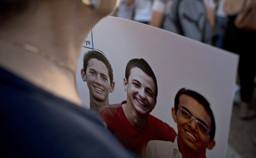 An Israeli woman holds a poster with photos of three Israeli teens, who were killed in the summer of 2014.