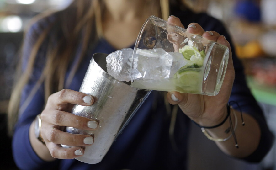 Bartender Rafaella Demelo adds sugar, 1.5 ounces of Leblon, and half a lime over ice in a shaker while preparing a caipirinha, Brazil's trademark cocktail.