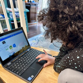 A San Diego Unified School District student works on her school-issued laptop computer to complete an assignment at home in San Diego on May 23, 2023.