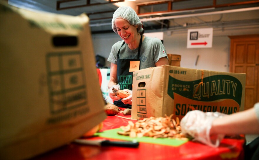 A volunteer peels sweet potatoes.