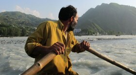 An oarsman navigates his inner-tube boat across the raging Swat River in northwest Pakistan. The bridge that once traversed the river was destroyed by the floods.
