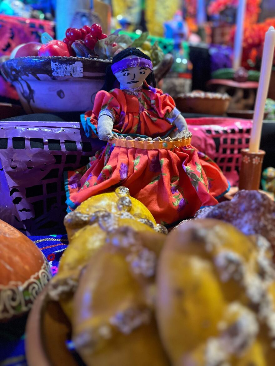 A doll wearing indigenous costume sits behind a bowl of pan de muerto at the Sherman Heights Community Center on Oct. 9, 2025.