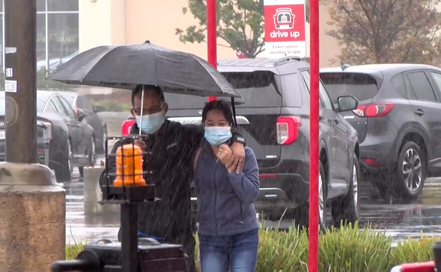 A couple wearing masks Dec. 14, 2021, outside a Mira Mesa shopping center ahead of the statewide indoor mask mandate coming into effect on Dec. 15, 2021.