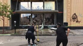 Community members in downtown La Mesa sweep up debris in front of the Randall Lamb Associates building that was burned on the inside, May 31, 2020. 
