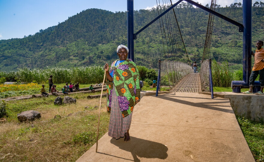Naomi Nibishaka crosses the newly constructed pedestrian bridge over a river. She's on her way to see her son and grandchildren, who live in a settlement on the other side.