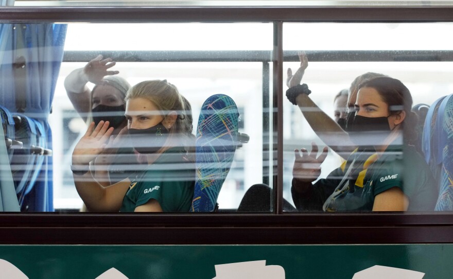 Australian softball players, the first foreign team to arrive for the Tokyo Olympic Games, wave from their bus after arriving at Narita International Airport on June 1.