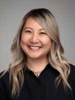 Woman smiling with light hair wearing a black shirt.