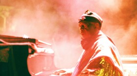 Sun Ra in orange light and haze plays piano and glares at camera.