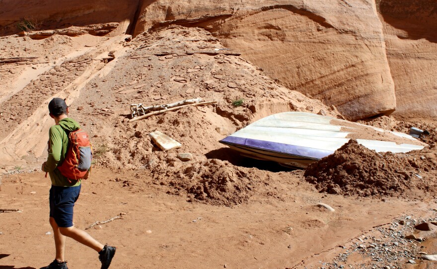 Eric Balken, with the Glen Canyon Institute, walks past a sunken speedboat in a side canyon in Glen Canyon National Recreation Area. Water levels in Lake Powell have steadily dropped, revealing areas that have been underwater for decades.