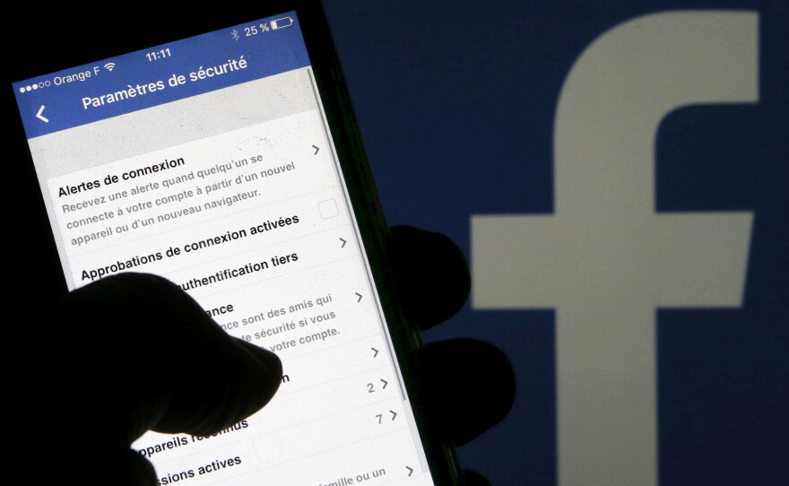 Facebook says it disagrees with how The New York Times is presenting data-sharing deals it has used for at least 10 years. Here, a man reads security parameters on his phone in front of a Facebook logo in Bordeaux, southwestern France.