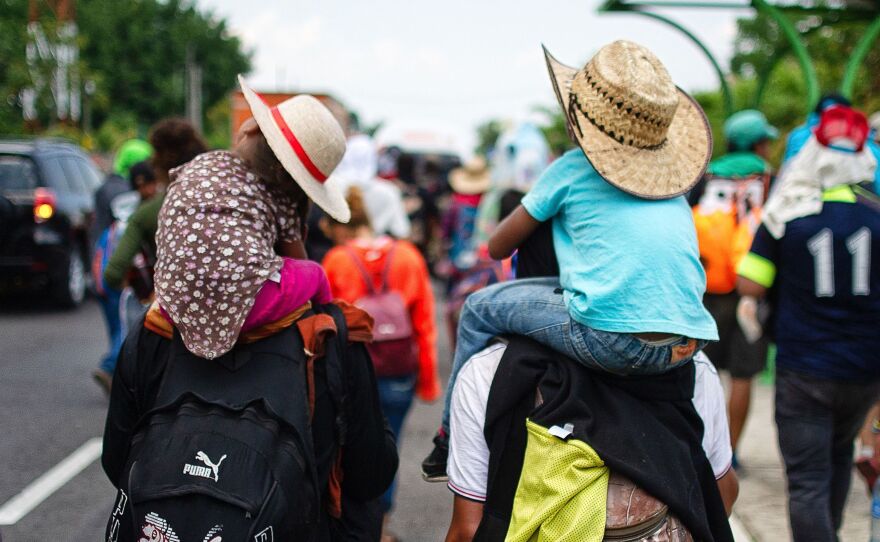 Children are carried on the shoulders of Central American migrants heading to the U.S. along the road between Metapa and Tapachula, Mexico, on April 12. President Trump has called for measures to close what he calls the asylum "loophole" amid a spike in border crossings.