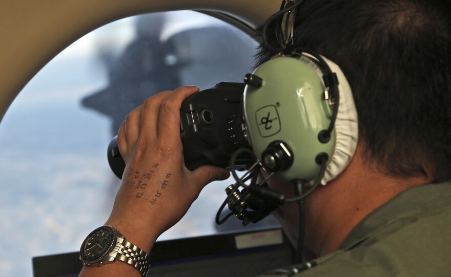 Flight Officer Jack Chen uses binoculars at an observers window on a Royal Australian Air Force P-3 Orion during the search for missing Malaysia Airlines Flight 370 in the southern Indian Ocean in March 2014.