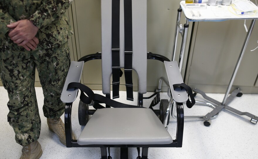In this photo reviewed by the U.S. military, a U.S. Navy nurse stands next to a chair with restraints and other tools used for force-feeding at tje detainee hospital at Guantanamo Bay in 2013.