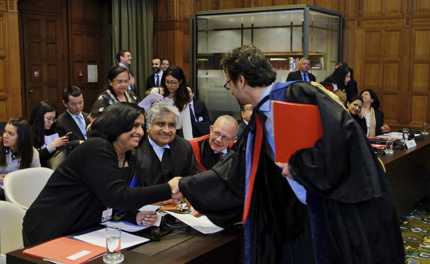 Members of the Indian delegation to the International Court of Justice, Neeru Chadha (left) and Harish Salve (center) greet a member of the Marshall Islands' legal team ahead of a preliminary hearing on nuclear disarmament at the International Court of Justice.
