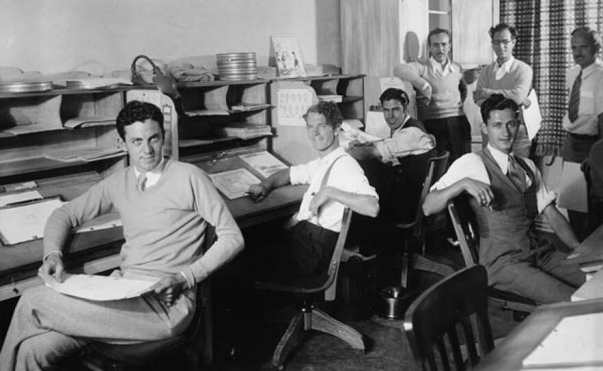 Walt Disney, left side standing, and some of his animators in the new animation building at Hyperion Studios. Seated L-R: Dave Hand, Johnny Cannon, Rudy Zamora, Les Clark. Standing: Walt Disney, Tom Palmer, Ben Sharpsteen. 1931.