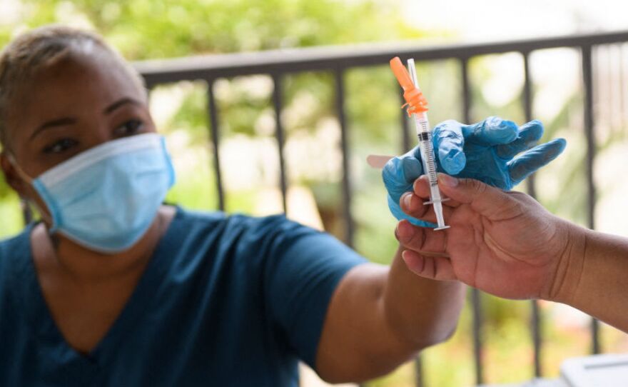 A nurse is handed a dose of the Pfizer Covid-19 vaccine before administering it to a college student during a mobile vaccination clinic at the California State University, Long Beach, on Aug. 11.