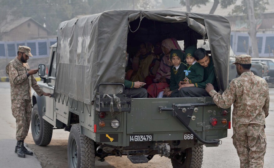 Pakistani soldiers escort students as they leave the Army Public School in Peshawar on Jan. 12. The school has reopened after last month's attack by the Pakistani Taliban that killed more than 130, most of them teenage students.