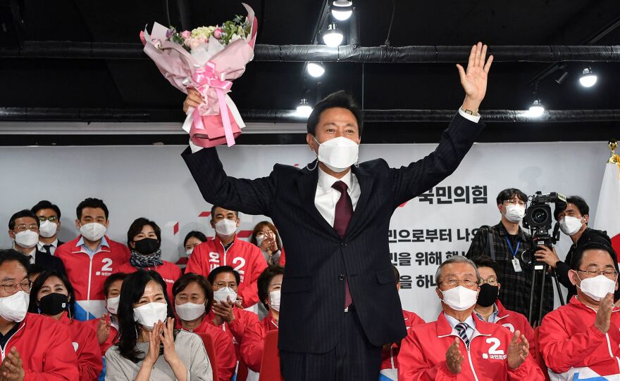 Oh Se-hoon, center, the mayoral candidate of the main opposition People Power Party, holds flowers as he celebrates with party members after exit polls showed he would win.