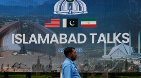 A police officer walks past a billboard regarding the United States and Iran negotiations, outside a media facilitation center in Islamabad, Pakistan, Saturday, April 11, 2026.