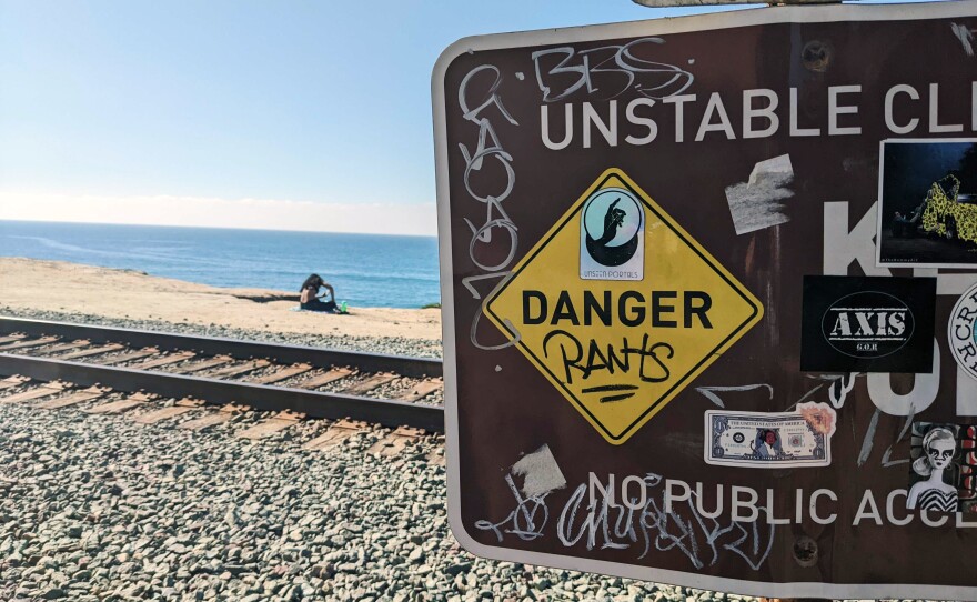 A woman sunbathing on the bluffs next to the train tracks in Del Mar despite the posted "No Public Access" sign, Jan. 21, 2021.