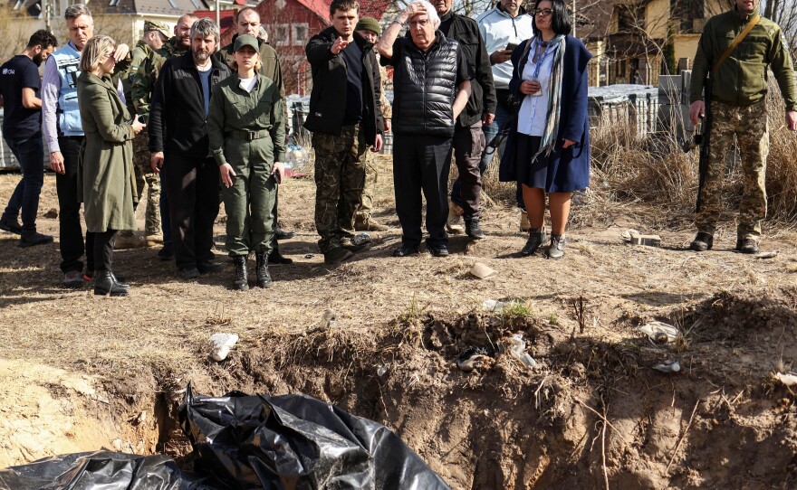 U.N. humanitarian chief Martin Griffiths puts his hand on his head as he reacts to the sight of a mass grave Ukrainians dug near a church in Bucha, on April 7. Griffiths said investigators will probe civilian deaths uncovered after Russian troops withdrew.