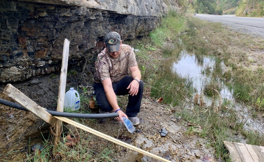 Jasper Davis gets drinking water from a mountain stream in Martin County, Ky. He says he's one of many in the struggling coal region who have trouble affording their water bill.