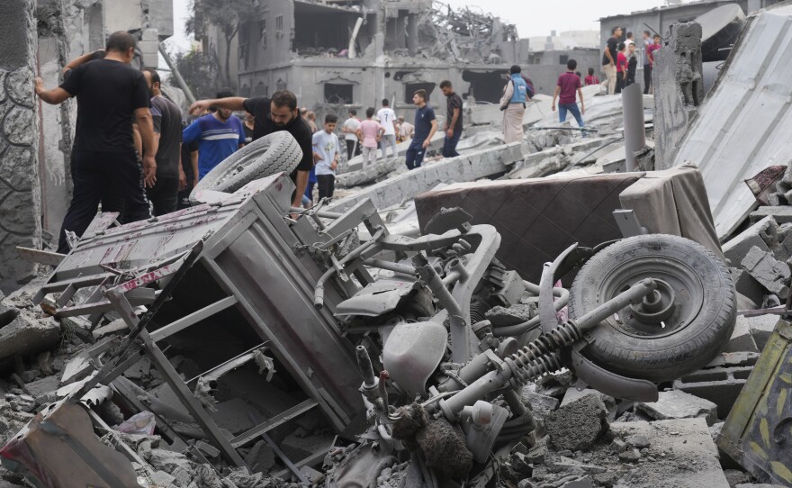 Palestinians walk about buildings destroyed in the Israeli bombardment in the Nusseirat refugee camp in the Gaza Strip on Sunday, Oct. 29, 2023.
