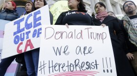 In this Jan. 25, 2017 file photo protesters hold signs as they listen to speakers at a rally outside of City Hall in San Francisco, Calif. 