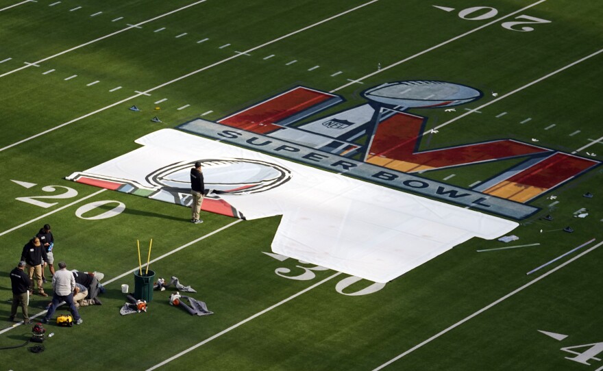 Workers paint a logo on the field at SoFi Stadium on Feb. 8.