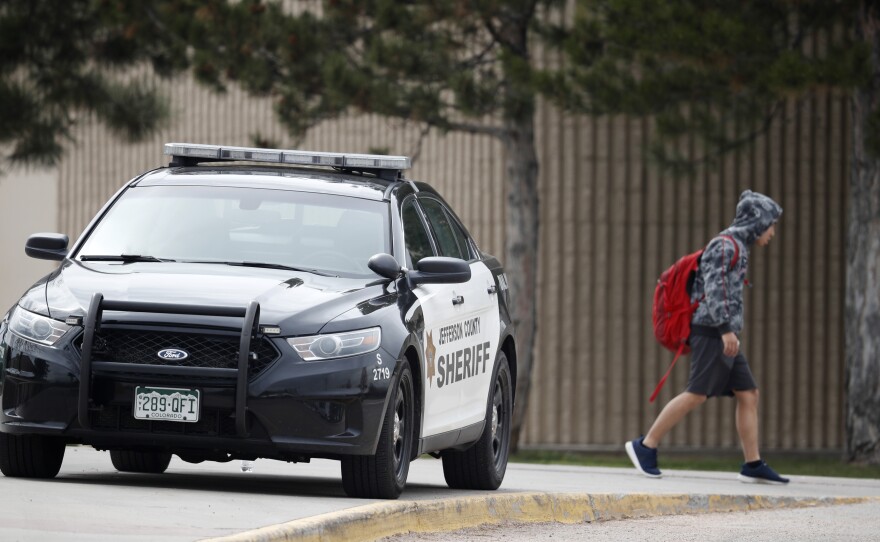 A student leaves Columbine High School late Tuesday in Littleton, Colo. Authorities say they are looking for a woman they say presented a credible threat ahead of the 20th anniversary of the mass shooting there.