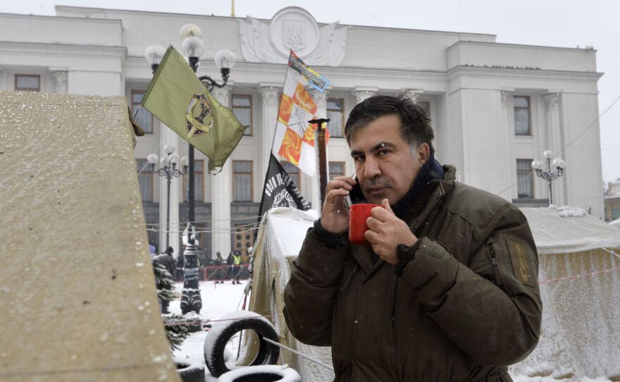Former Georgian President Mikhail Saakashvili talks on a cellphone at a barricade in front of the Ukrainian Parliament in Kiev, where his supporters are camping.