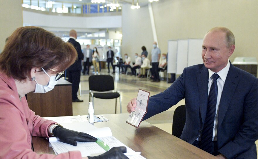 Russian President Vladimir Putin shows his passport to a member of an election commission as he arrives to take part in voting at a polling station in Moscow on Wednesday.