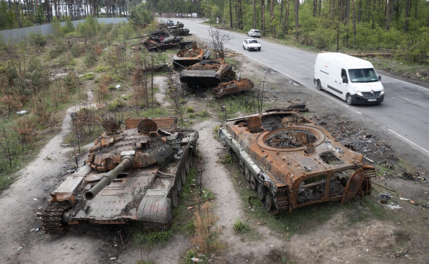 Cars pass destroyed Russian tanks from an earlier battle against Ukrainians in the village of Dmytrivka, close to Kyiv, Ukraine, on Monday. With Russian troops gone from the Kyiv region, life is returning to the city. But heavy fighting takes place daily in the east and the south of the country.
