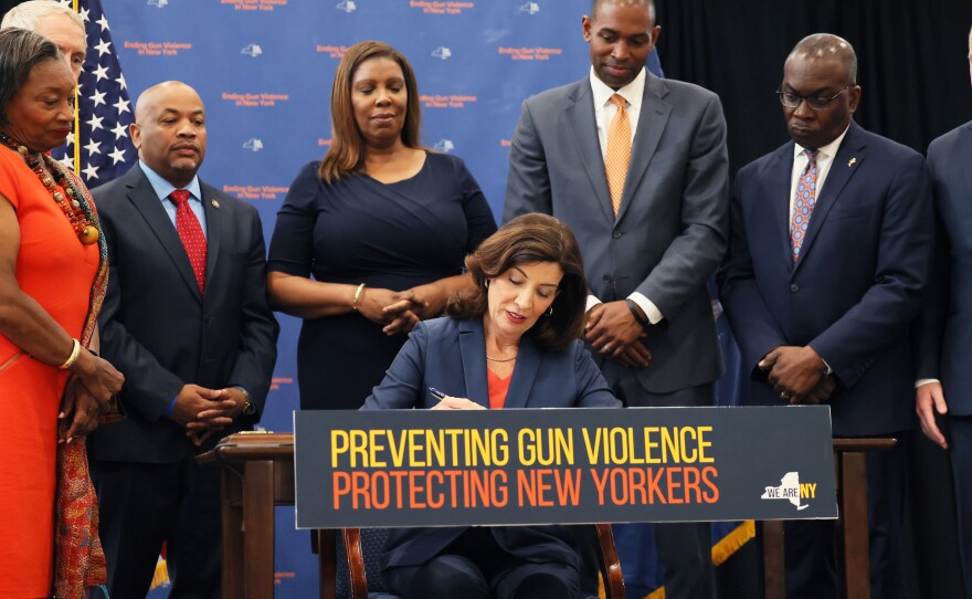 New York Gov. Kathy Hochul signs legislation limiting body armor access as she is surrounded by lawmakers during a bill-signing ceremony on June 6 in New York City.