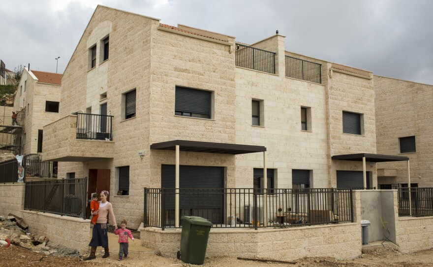 An Israeli settler and her two children leave a friend's house in a new housing development under construction in Ariel, West Bank.