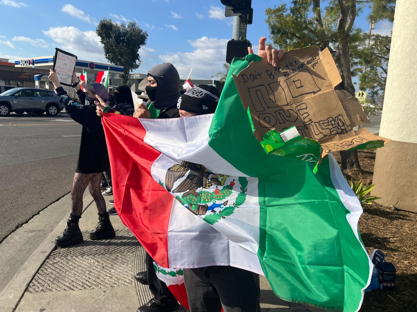 A demonstrator holds a Mexican flag at a protest on Washington Avenue and Escondido Boulevard in Escondido on Jan. 29, 2025.