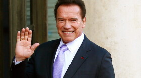 Arnold Schwarzenegger waves as he arrives at the Elysee Palace prior to a meeting on climate change in Paris, Dec. 12, 2017. 