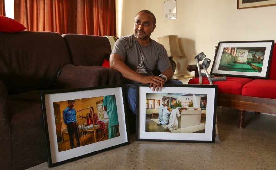 Gautam Lewis, now 39, poses with some of the photographs he has taken that trace the life and work of Mother Teresa, who took him in when he was 3. The images are part of an exhibition Lewis has staged in Kolkata as an homage to the woman he calls his "second mother."