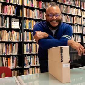 T.J. Tallie poses with a box of materials on Marti Mackey in the Lambda Archives of San Diego on Jan. 15, 2025.