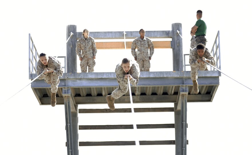 Female Marine recruits climb across a rope obstacle during the confidence course portion of basic training, March 9, 2021.