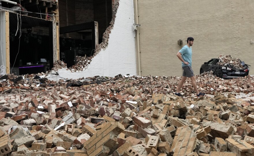 A man walks through fallen bricks from a damaged building in the aftermath of a severe thunderstorm on Friday, in Houston.