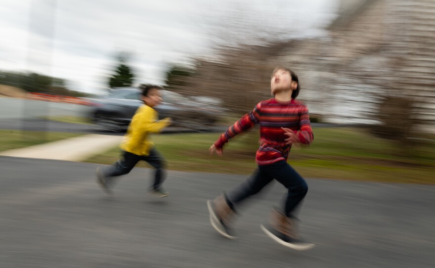 Brothers Hayle (left) and Henry Pham run during a game of football, as their father, Hansel, throws a ball in the air on Jan. 26, 2020.