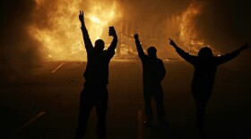 People watch as stores burn Tuesday in Ferguson, Mo., Nov. 25, 2014.
