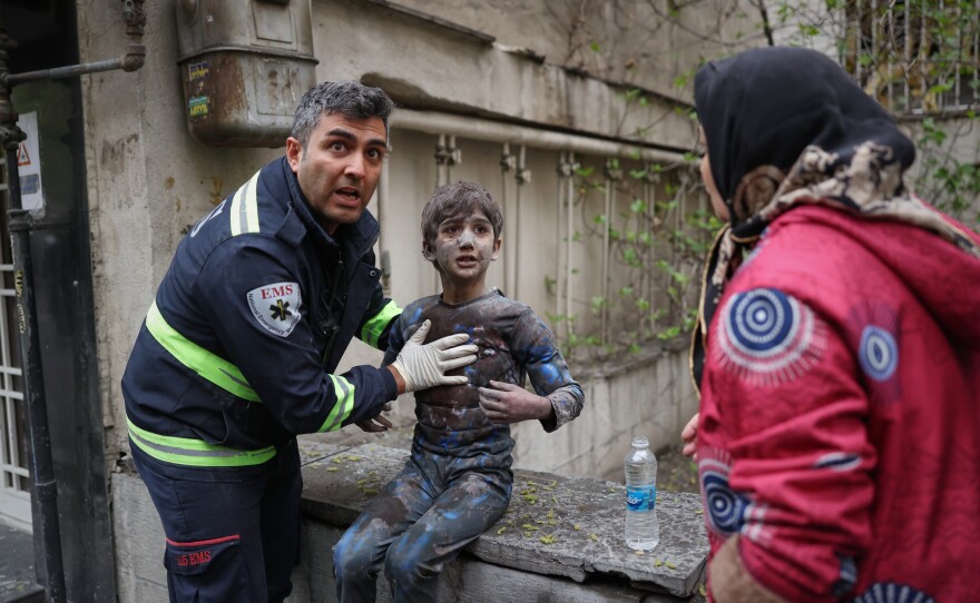 A first responder assists an injured boy following a strike that hit a residential building amid the U.S.-Israeli military campaign in Tehran, Iran, Saturday, March 28, 2026.