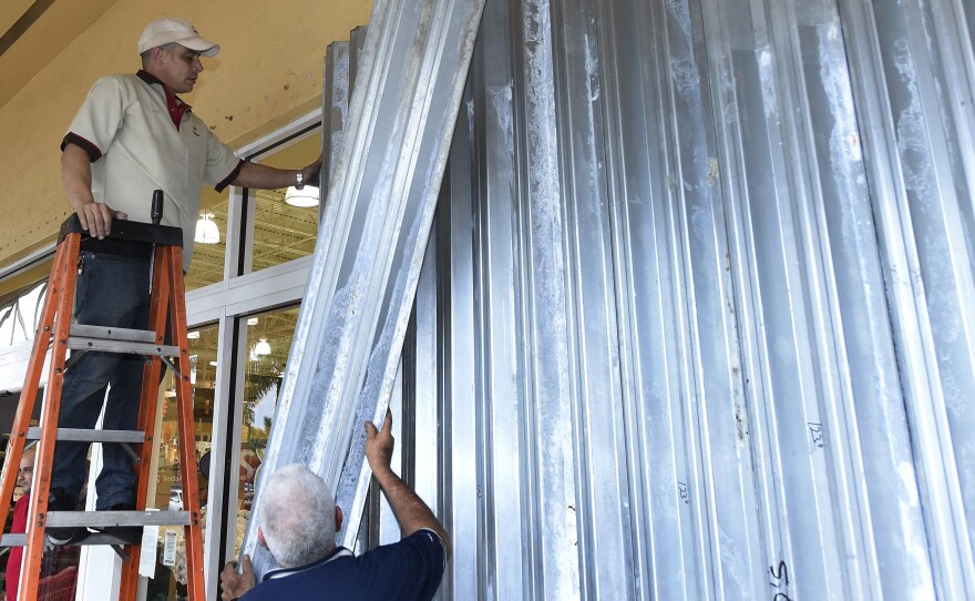 Workers put up shutters at a strip mall in preparation for Hurricane Matthew in Miami on Thursday. Some 3 million people on the Southeast coast faced an evacuation order.