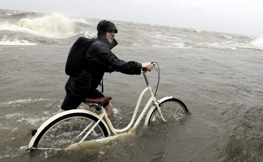 Tyler Holland guides his bike through the water as winds from Tropical Storm Barry push water from Lake Pontchartrain over the seawall Saturday.