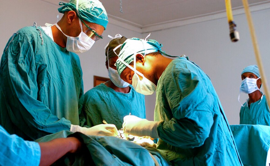 Dr. Dilan Ellegala, left, supervises Dr. Emmanuel Nuwas of Tanzania as he inserts a shunt in a baby with hydrocephalus. Ellegala has played a key role in training local doctors, as described in the new book A Surgeon in the Village. Early on, he trained a hospital staffer who wasn't a doctor to do brain surgery.