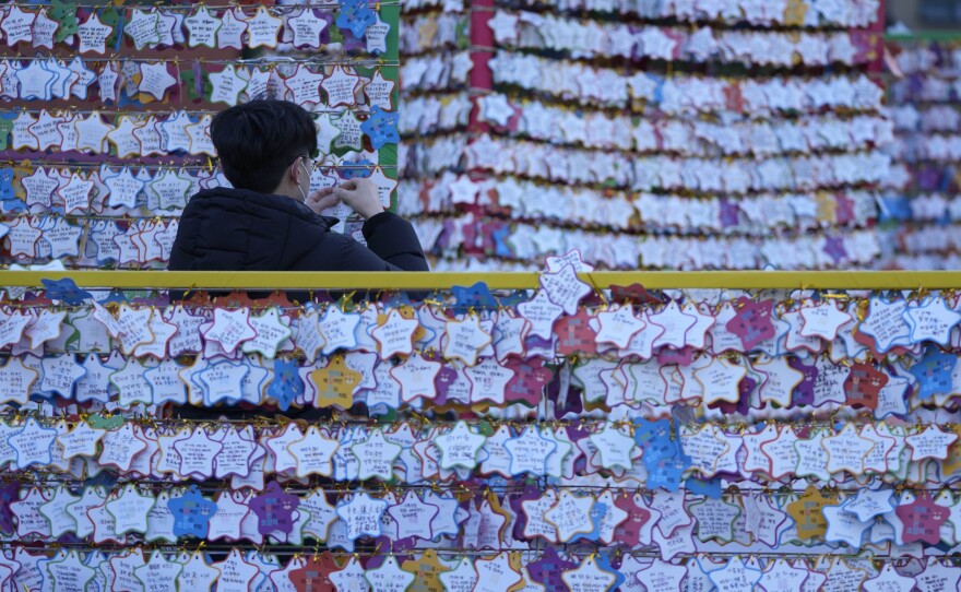 A man hangs a paper note bearing his New Year wishes on New Year's Eve at the Jogye temple in Seoul, South Korea, on Friday.