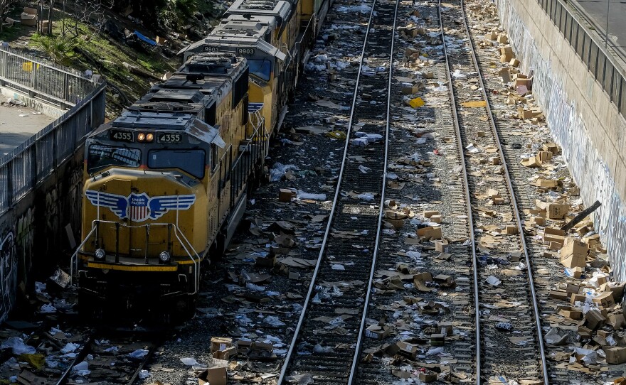 A train passes by as shredded boxes and packages at a section of the Union Pacific train tracks in downtown Los Angeles Friday, Jan. 14, 2022.